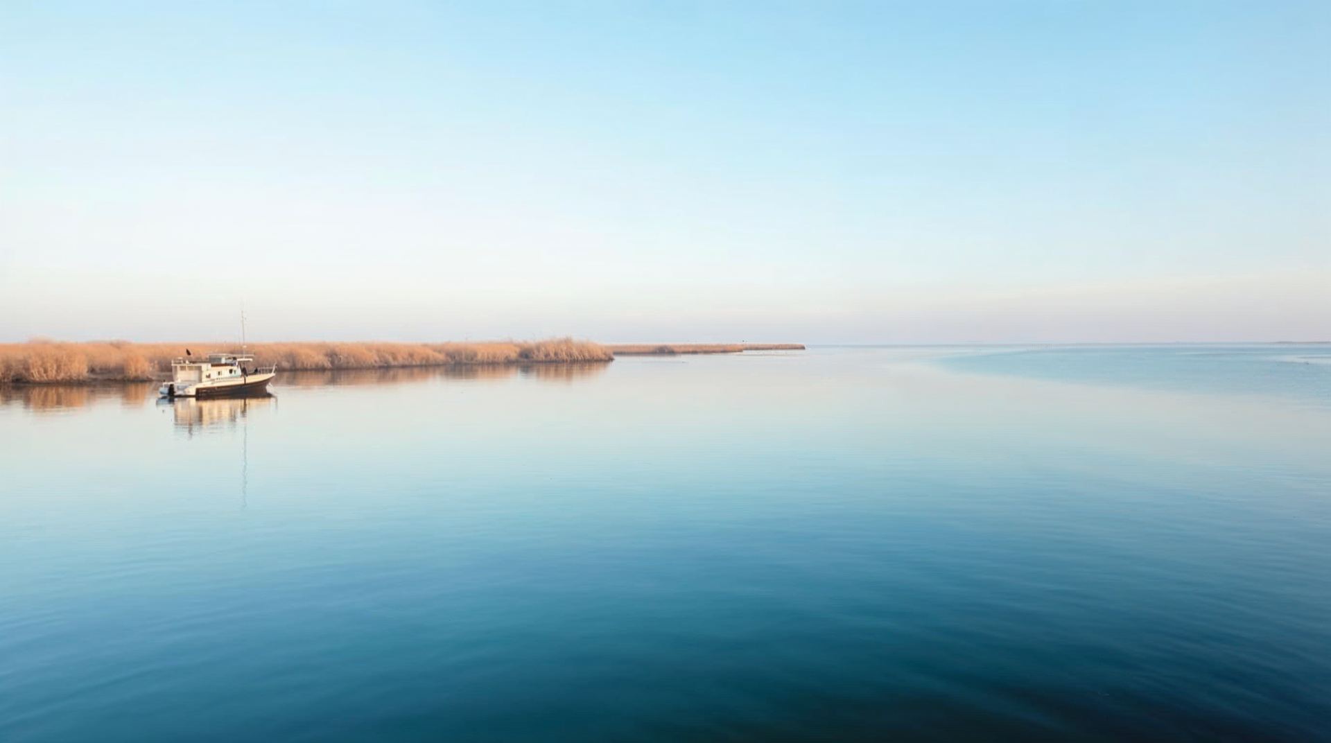 A small fishing boat on still blue water at Lake Ogallala in Nebraska at early morning
