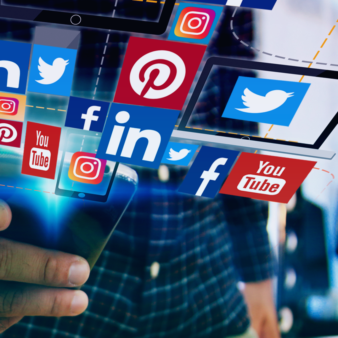 man holding a phone with a design of different social media icons floating in the air from the phone