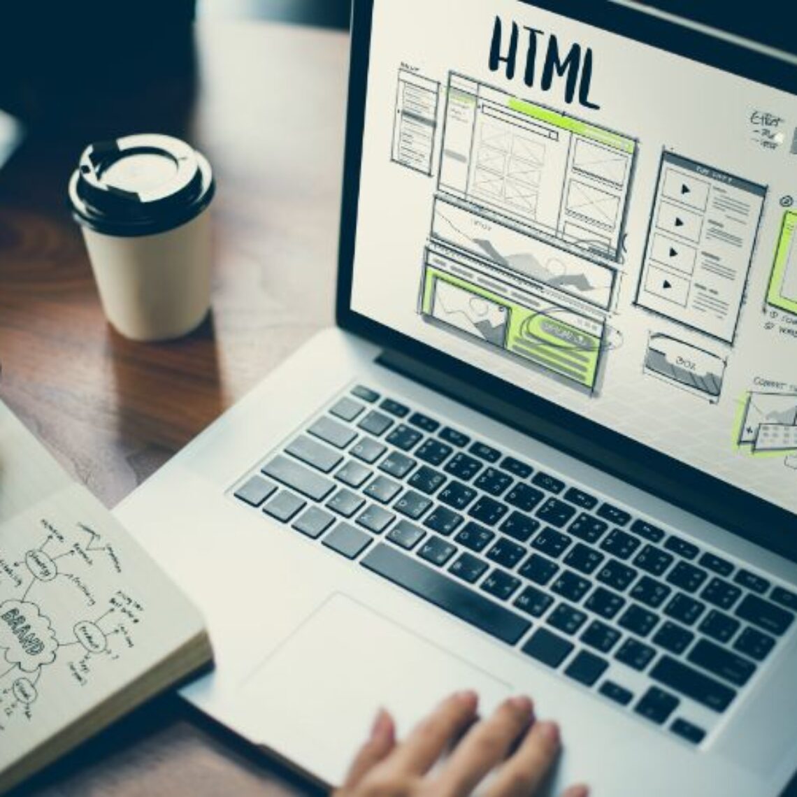 person working at a computer with a website wireframe mockup and writing down the web design price for the project